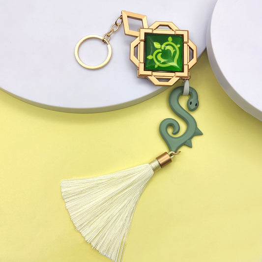 Genshin Baizhu Vision Keychain, Features Glow-in-the-Dark: gold, green stylized snake motif, ornamental cartoon style